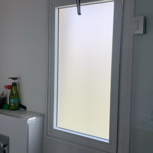 חלון זכוכית עם מסגרת לבנה בחדר אמבטיה