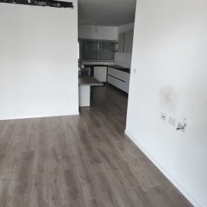 רצפה נקייה בחדר ריק עם מטבח ברקע