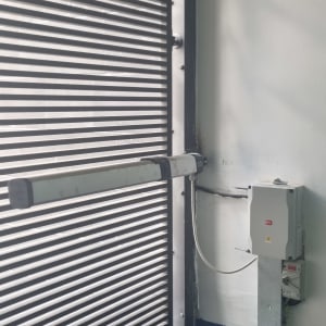 שער חשמלי עם מנגנון פתיחה וסגירה על קיר