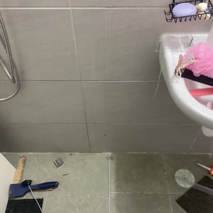 כלי עבודה וחלקי מקלחון על רצפת חדר רחצה במהלך עבודת תיקון או התקנה