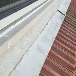 איטום חלון עם חומר איטום לבן על אדן בטון