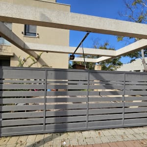 שער חשמלי מתכת אפור עם קורות אופקיות