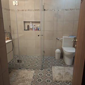 חדר אמבטיה עם מקלחון זכוכית ורצפת אריחים מעוצבת
