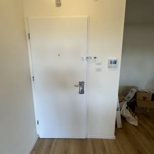 דלת לבנה עם ידית מתכת ובריח עליון