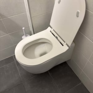 אסלה מותקנת בחדר אמבטיה עם אריחים אפורים