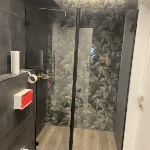 מקלחון זכוכית עם קיר עלים ודלתות שקופות