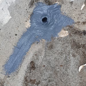 חומר איטום אפור סביב פתח ניקוז על גג