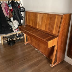 פסנתר עומד ליד מתלה בגדים ונעליים על הרצפה