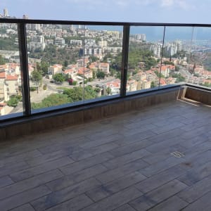 מרפסת עם רצפת עץ וניקוז, נוף עירוני ברקע