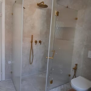 מקלחת עם דלת זכוכית וברזים מוזהבים