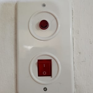 מתג חשמלי עם כפתור אדום על קיר לבן