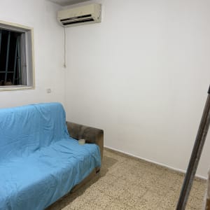 סלון עם ספה מכוסה בכיסוי כחול ומזגן על הקיר