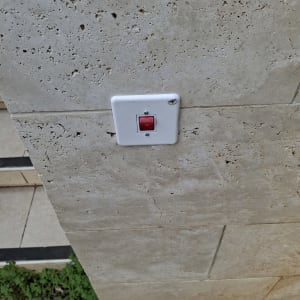מתג חשמלי עם כפתור אדום על קיר אבן
