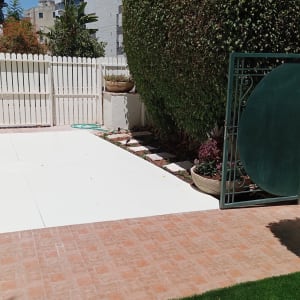 צינור השקיה ירוק, עציצים עם צמחים, גדר עץ לבנה