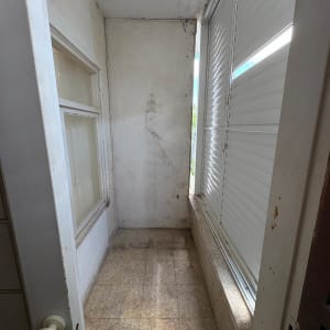 מרפסת קטנה עם קירות לבנים ותריסים סגורים