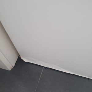 דלת לבנה עם פגם בתחתית על רצפת אריחים אפורה