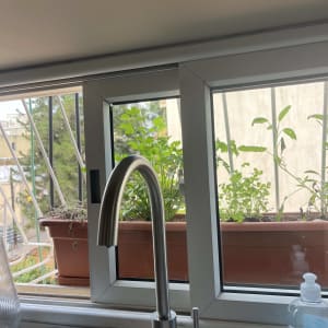 ברז מטבח עם חלון וצמחי תבלין ברקע