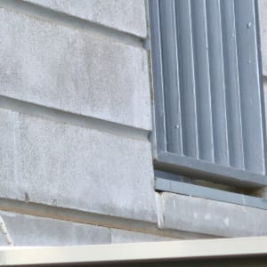 קיר עם סדקים ליד חלון מתכת אפור