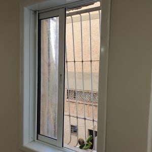 חלון נקי עם מסגרת לבנה וסורגי מתכת