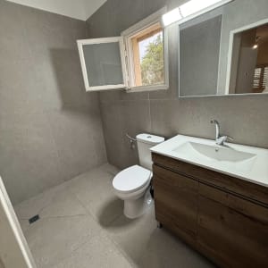 חדר אמבטיה משופץ עם כיור, אסלה וחלון פתוח