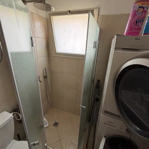 חדר אמבטיה עם מקלחון, מכונת כביסה ומייבש