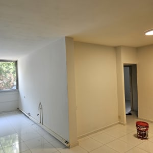 דלי צבע אדום על רצפה לבנה בחדר ריק