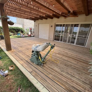 דק עץ עם מכונת ליטוש תחת פרגולה מעץ