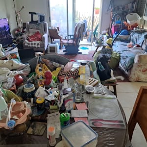 סלון ופינת אוכל עמוסים בחפצים לפני תהליך סידור בית