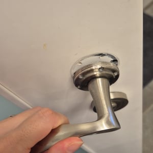 ידית דלת מתכתית על דלת לבנה