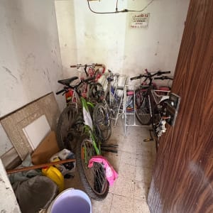 חדר עם אופניים, דלי סגול, וציוד נוסף על הרצפה