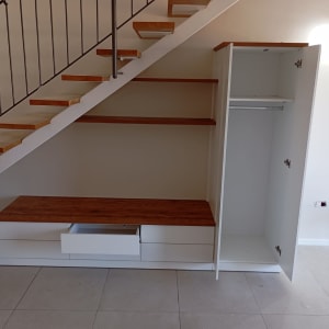 ארון פתוח עם מדפים ומגירה מתחת למדרגות