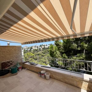 מרפסת עם סוכך בד מפוספס ונוף ירוק