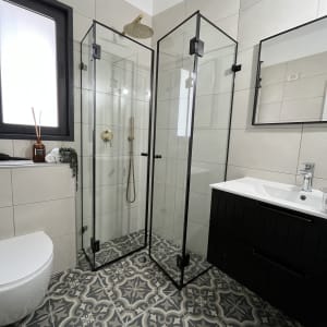 מקלחון זכוכית עם ראש מקלחת מוזהב בחדר אמבטיה מודרני