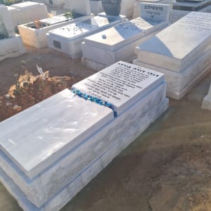 מצבות בבית קברות עם כיתוב בעברית ואבנים קטנות