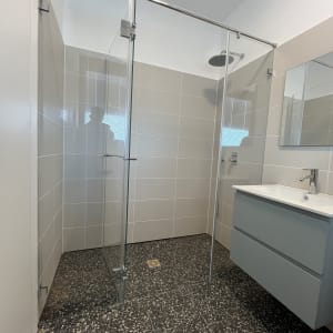 מקלחון זכוכית עם כיור ומראה בחדר אמבטיה מודרני