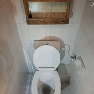 אסלה לבנה עם מדף עץ מעליה