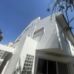 בניין לבן עם חלונות זכוכית ועצים ברקע