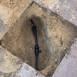 צינור שחור חשוף באדמה עם חיבורי פלסטיק