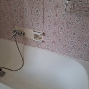 אמבטיה עם אריחים ורודים וברז מקלחת