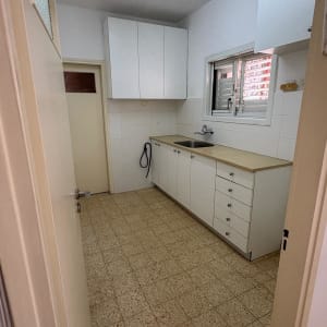 מטבח ריק עם ארונות לבנים וכיור