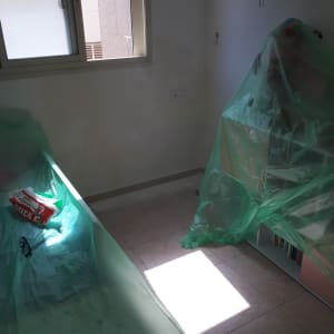 חדר עם קירות מוכנים לצביעה, כיסויים ירוקים על רהיטים