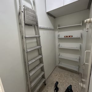 סולם וכלי עבודה בחדר קטן עם מדפים