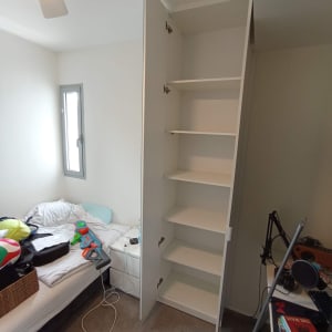 ארון לבן פתוח עם מדפים ריקים בחדר שינה