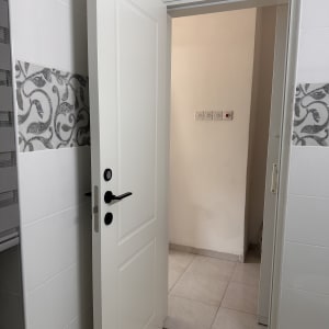 דלת לבנה פתוחה בחדר אמבטיה עם אריחים מעוצבים