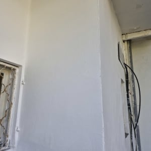 קיר ותקרה צבועים בלבן מעל חלון עם סורג