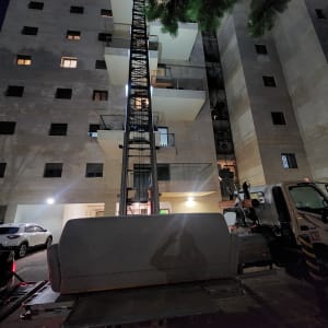 מנוף מרים חפץ מול בניין מגורים בלילה