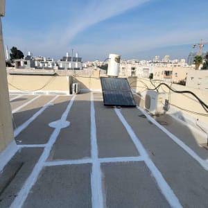 גג עם קווים לבנים לאיטום, דודי שמש ומזגנים