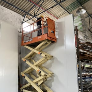 עובד על פיגום נייד בתוך מבנה תעשייתי