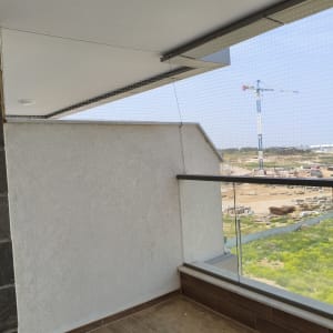 רשת יונים מותקנת במרפסת עם נוף לבנייה