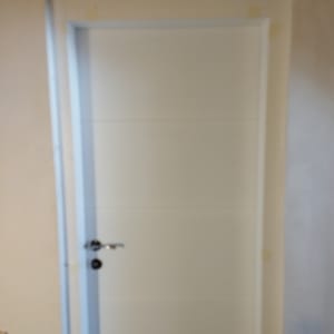 דלת לבנה עם ידית כסופה במסגרת קיר